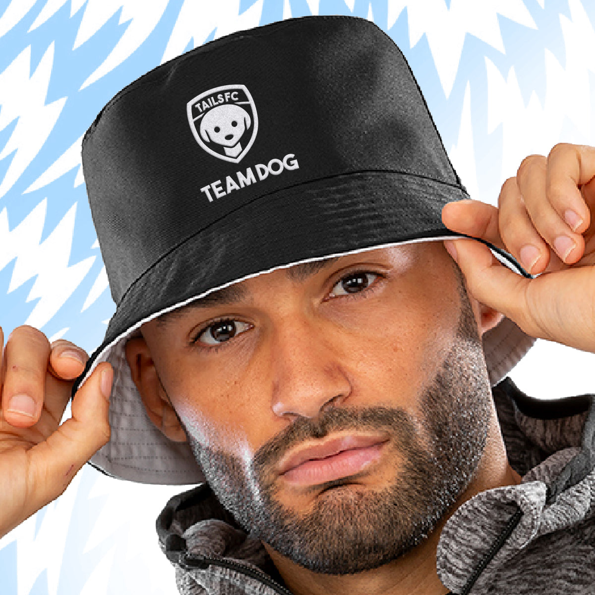 Man wearing a Tails FC  black bucket hat with 'TEAM DOG' branding against a blue abstract background