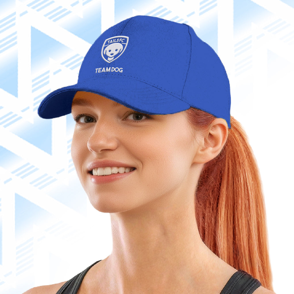 Woman wearing a blue cap with Tails FC  logo and text on a light blue geometric patterned background
