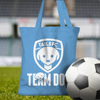 Blue tote bag with 'TAILSFC Team Dog' design on grass with a soccer ball.