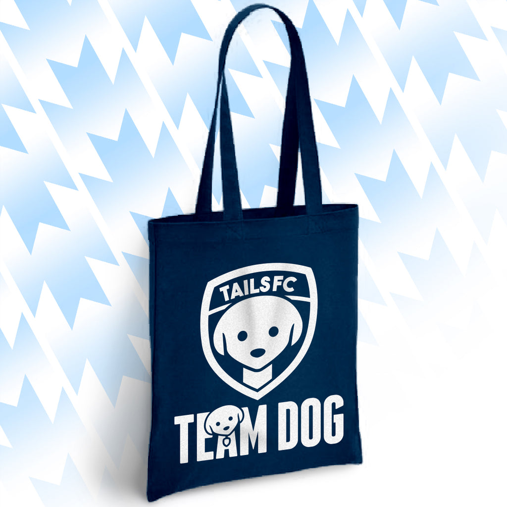 Navy blue tote bag with 'TAILSFC Team Dog' logo on a light blue abstract background