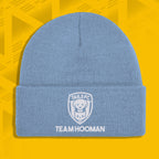 Blue beanie with 'TAILS FC' and 'TEAM HOOMAN' text on a yellow geometric patterned background