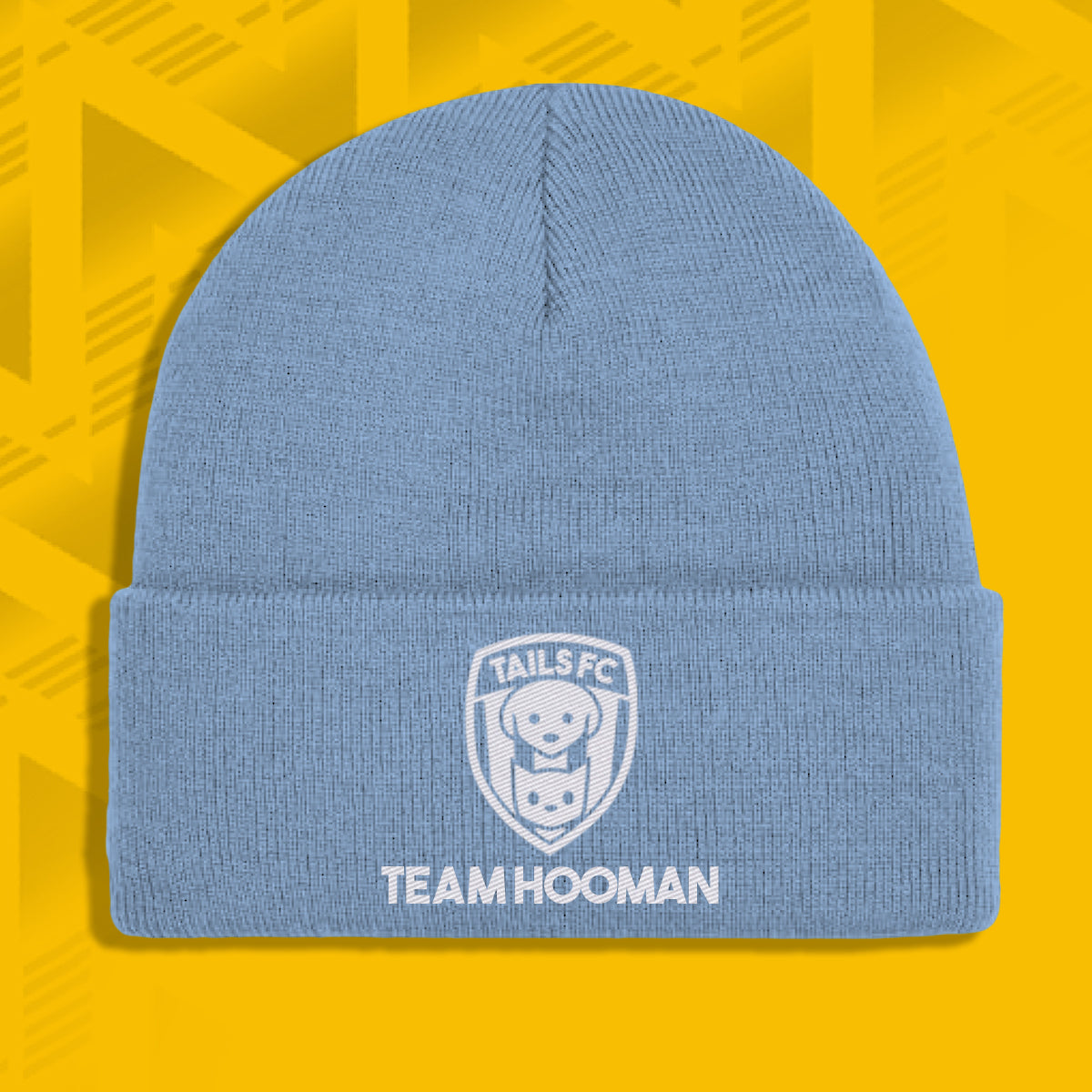Blue beanie with 'TAILS FC' and 'TEAM HOOMAN' text on a yellow geometric patterned background
