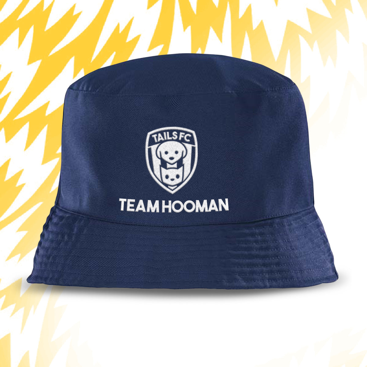 Navy bucket hat with 'Tails FC' logo and 'Team Hooman' text on a yellow and white abstract background