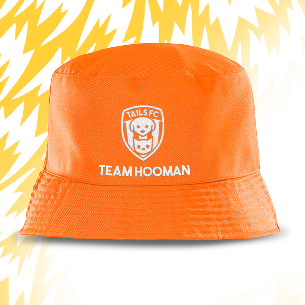 Orange bucket hat with 'Tails FC' and 'Team Hooman' text on a white background with yellow abstract patterns.