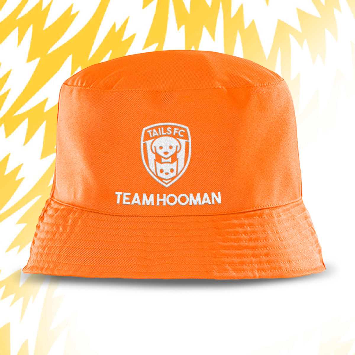 Orange bucket hat with 'Tails FC' and 'Team Hooman' text on a white background with yellow abstract patterns.