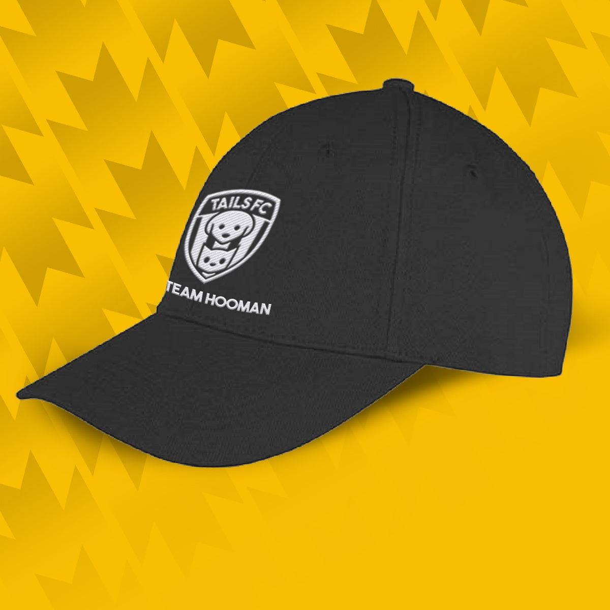 Tails FC Black cap with Team Hooman logo and text on a yellow geometric patterned background