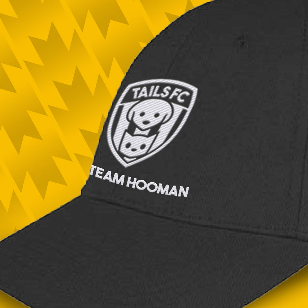 Black cap with 'TAILS FC' and 'TEAM HOOMAN' text on a yellow geometric pattern background