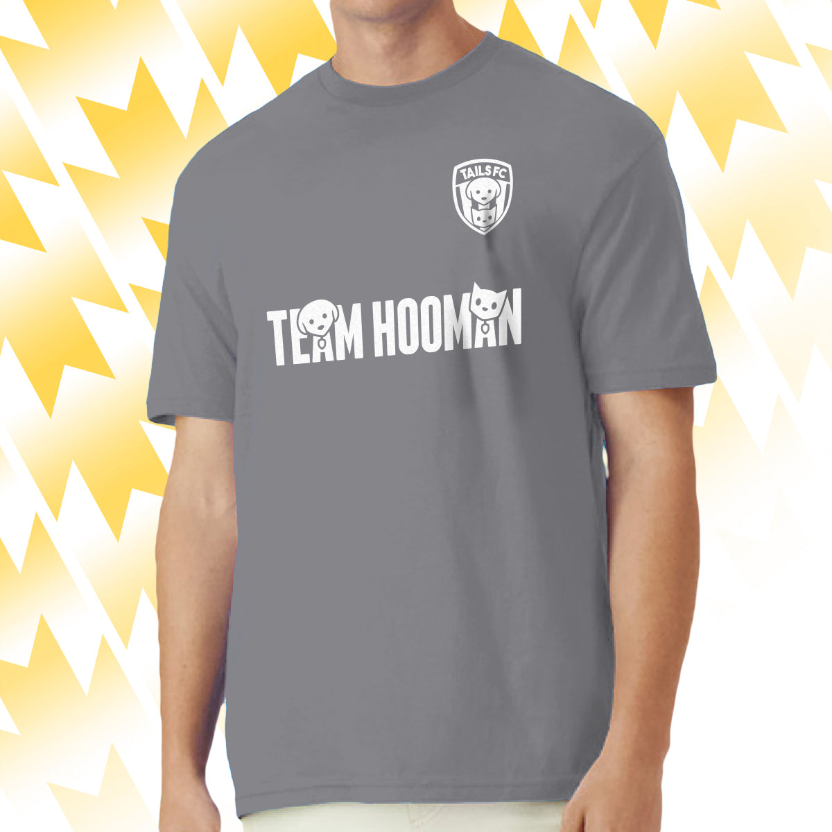 Man wearing a gray Tails FC t-shirt with 'Team Hooman' text and logo on a yellow and white abstract background