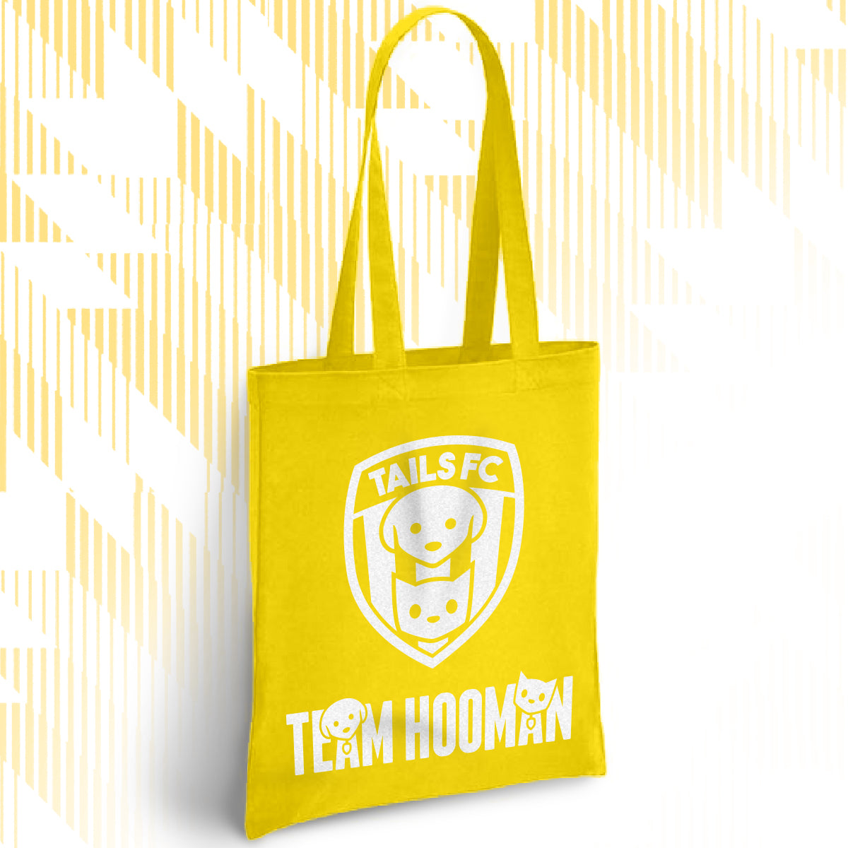 Yellow tote bag with 'TAILS FC' and 'TEAM HOOMAN' text on a white background