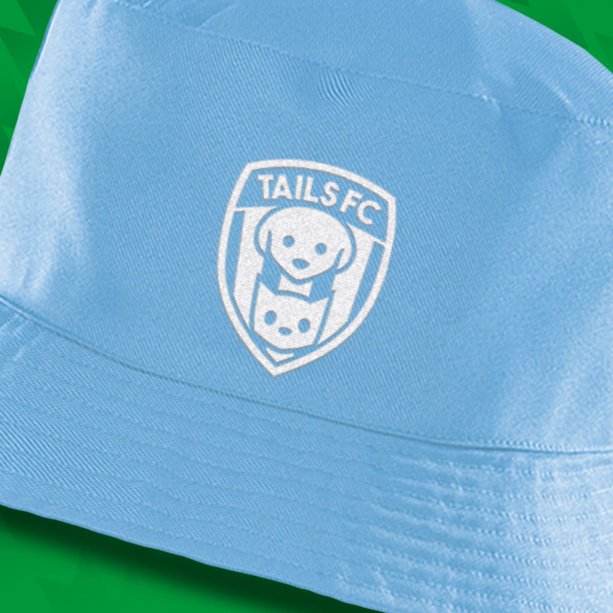Light blue cap with TAILS FC logo on a green background