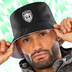Person wearing a black Tails FC bucket hat with a logo on a green and white patterned background